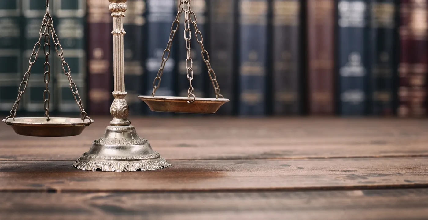 Justice scales with law library in background