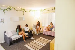 Four students sitting on couch, chair and love seat in their neatly decorated apartment living room